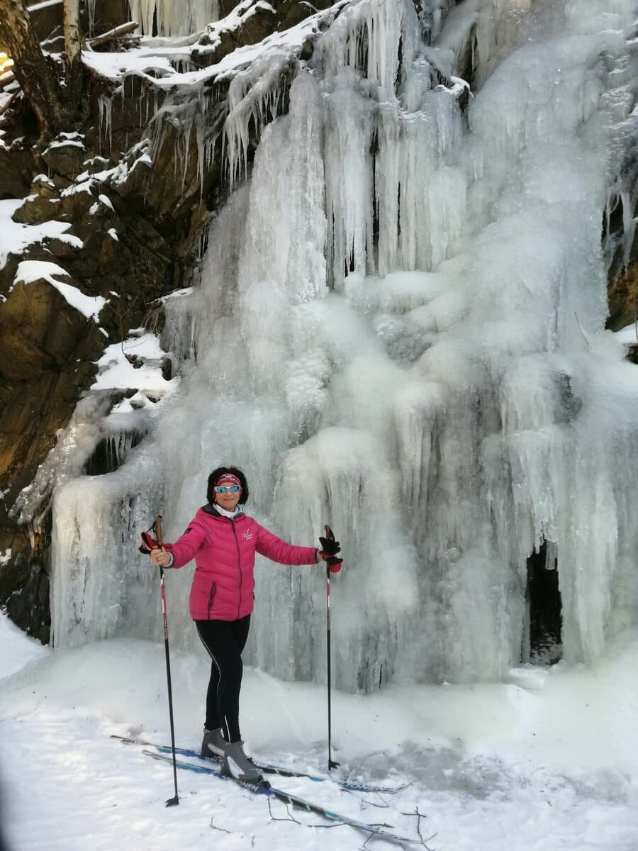 Anne Vierling mit Skistöcken vor einem gefrorenen Wasserfall